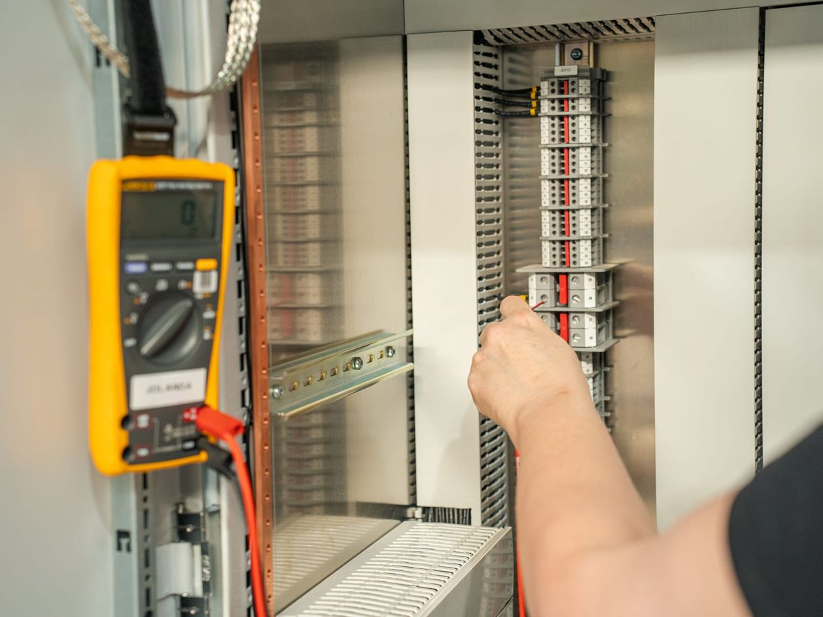 Monteur van SPARQ meet met een multimeter aan een paneel in de werkplaats