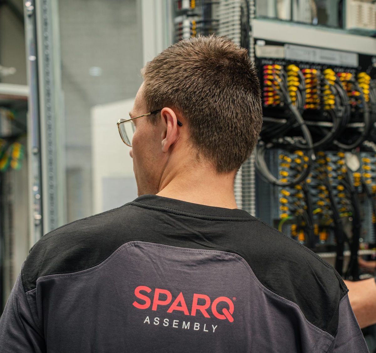 Monteur in SPARQ-werkkleding bedraadt een besturingspaneel in de werkplaats