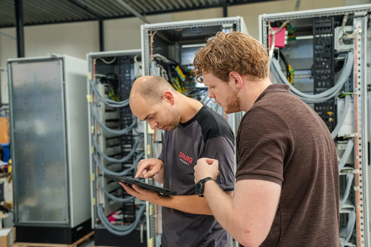 Twee SPARQ-medewerkers controleren een rij panelen aan de hand van een tablet